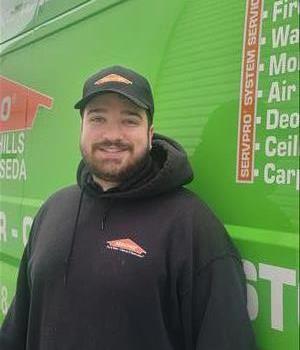 Servpro employee in front of Servpro vehicle smiling