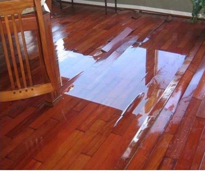 Wood floor flooded by water damage showing buckling