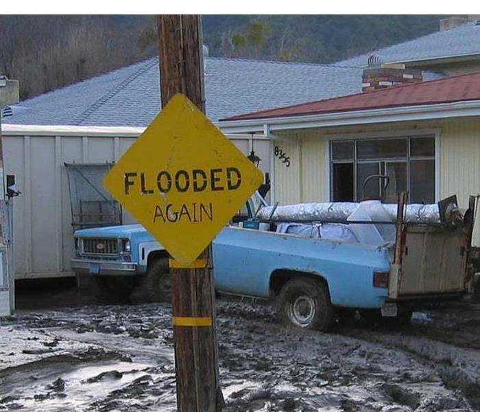 muddy driveway with flooded again sign